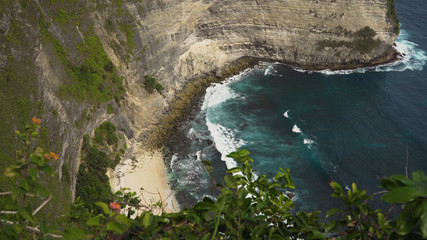 Seascape, rocky coast, with wild beach, ocean, blue sea, waves, Nusa Penida, Indonesia. Ocean with waves and rocky cliff. Travel concept