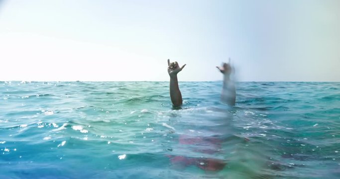 Man diving underwater and doing rock and roll hand gesture