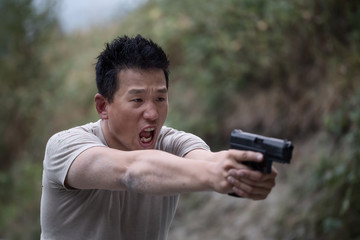 Man holding a gun is practicing at a gun range.