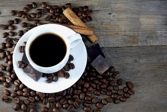 Top view of a cup of coffee with bunch of coffee beans and space for text on a wooden background.