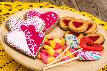 Set of sweets in the shape of heart on plate on wooden background