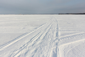 Fototapeta na wymiar Trace of a snowmobile on a snowy surface of frozen reservoir at dawn, Ob reservoir, Siberia, Russia