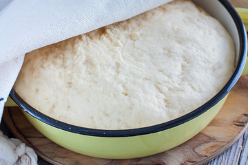 Yeast dough raw in a bowl on a wooden table. Country style, selective focus