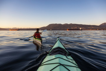 Naklejka premium Girl Kayaking during a colorful and vibrant Sunset. Taken near Jericho Beach, Vancouver, British Columbia, Canada.