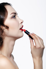 Portrait of young brunette woman. Girl with lipstick in hand. Female lips beauty makeup concept