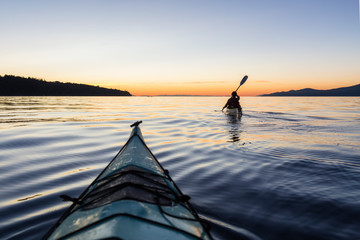 Adventure Woman Kayaking on a Sea Kayak during a Vibrant Sunset. Taken near Jericho Beach, Vancouver, BC, Canada.
