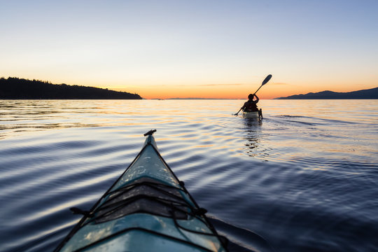 Adventure Woman Kayaking on a Sea Kayak during a Vibrant Sunset. Taken near Jericho Beach, Vancouver, BC, Canada.
