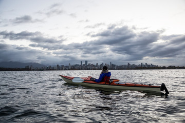 Adventure Woman is Kayaking in Vancouver during Dramatic Sunrise.