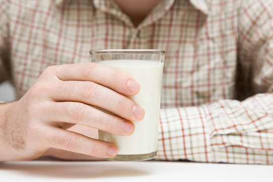 In the morning man drinking a glass of milk in the kitchen at home. Healthy drink concept.
