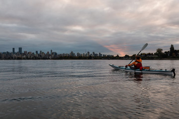 Obraz premium Adventure woman kayaking on a sea kayak in Vancouver, British Columbia, Canada. Taken during a cloudy sunrise.