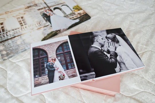 Pages with wedding photos of a photobook or photo album on bed.