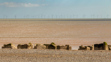 North Sea coast, pebble beach, stones and wind turbine, near Kilnsea, East Riding of Yorkshire, UK