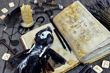 Scary doll, old book with black magic spells and runes on witch table. Occult, esoteric, divination and wicca concept. Halloween vintage background