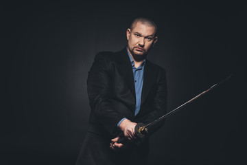 serious man in suit with katana on black