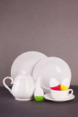 set of white utensils for Easter tea drinking and decorative cheerful eggs. Spring home concept