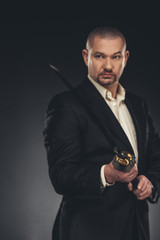 handsome mature man in suit with katana sword on black