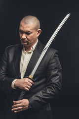 man in suit with katana sword isolated on black
