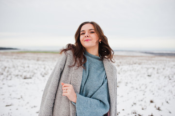 Gentle girl in gray coat against snow landscape.