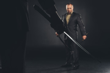 handsome modern samurai in suit ready to fight on black