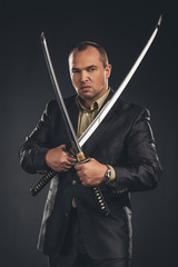 angry man in suit with katana sword isolated on black