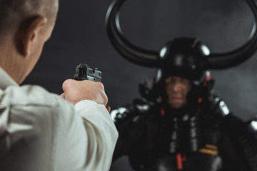 close-up shot of man aiming on armored samurai with gun