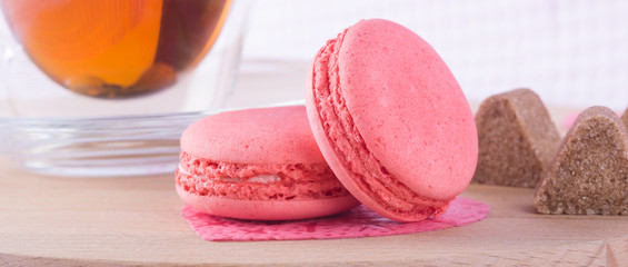 Macaron cakes on a wooden board, like a background to the day of the holy valentine, with tea