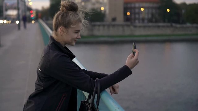 Teenage girl taking selfie photo on the bridge in the city
