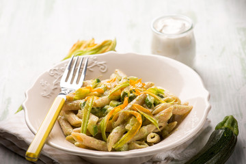 pasta with zucchinis flowers and cream sauce or yogurt, selective background