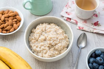 Porridge oats, scottish oats or oatmeal served with nuts, fruits, berries and green tea. Healthy breakfast, dieting, healthy eating concept