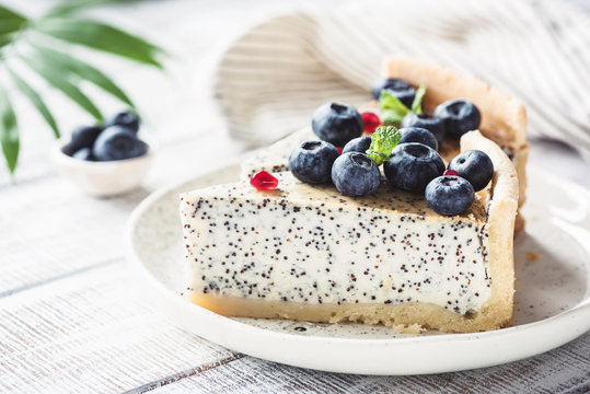 Cheesecake with poppy and blueberries on white plate. Closeup view, toned image