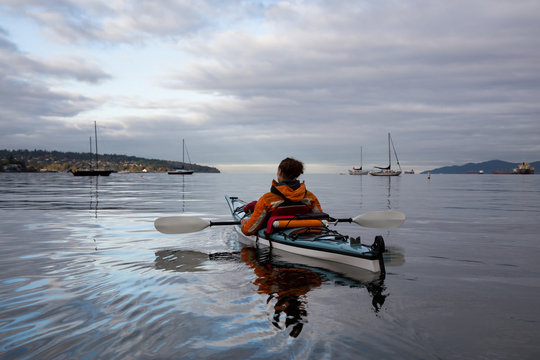 Adventurous woman is kayaking on a sea kayak during a vibrant morning. Taken in Vancouver, British Columbia, Canada.