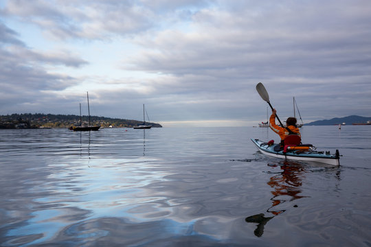 Adventurous woman is kayaking on a sea kayak during a vibrant morning. Taken in Vancouver, British Columbia, Canada.