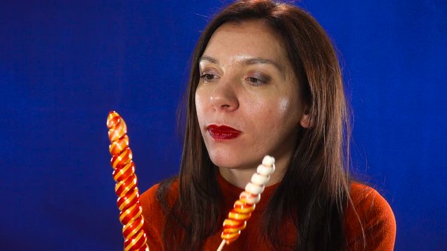 A charming European adult woman eroticly sucks a candy.