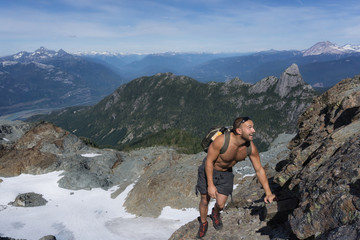 Adventurous male is climbing up the side of a rocky mountain during a sunny summer day. Taken near Squamish, North of Vancouver, British Columbia, Canada.
