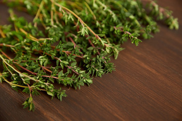 Branch of thyme on a dark wooden board. Free place for the inscription.