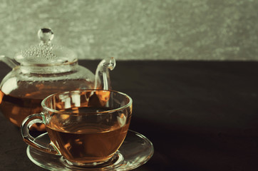 Cup of delicious herbal tea and glass teapot.