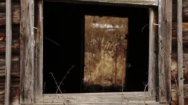 View through the glassless window inside a wooden abandoned house