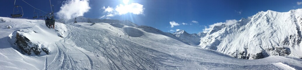 Fototapeta na wymiar Panaramic Snow Covered Mountains with Sun and Blue Sky