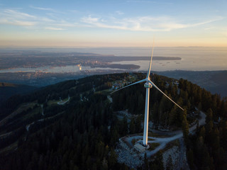 Aerial view of the wind turbine on top of the mountain during a vibrant summer sunset. Taken in North Vancouver, British Columbia, Canada.