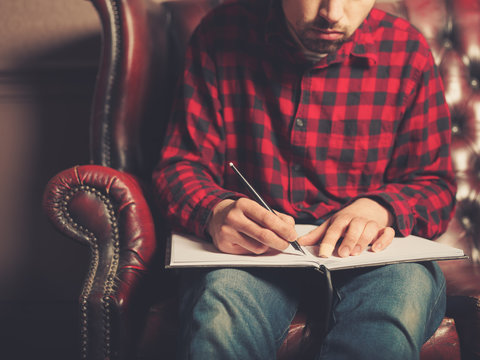 Young man on sofa writing in notebook