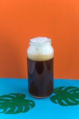 cold coffee in the bottleand paper monstera leaves