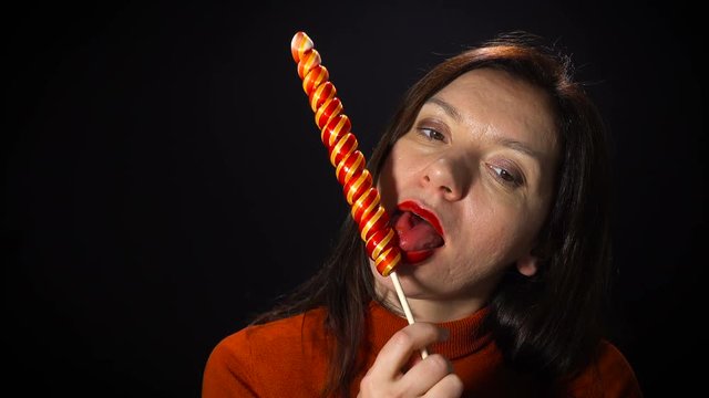 Beautiful woman sucks lollipop.