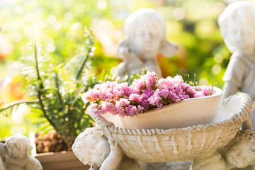 Purple flower on white old Potted statue in the garden with light.