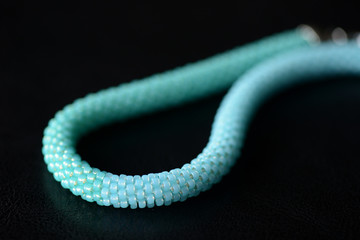 Obraz premium Seed bead necklace aquamarine color on a dark background close up