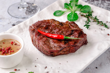 Top view close up, grilled beef steak with rosemary, herbs and spices on gray concrete background. and glass of red wine on table, restaurant kitchen concept