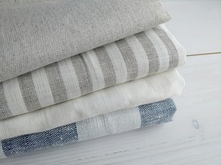 Pile of striped white grey blue red linen cotton fabrics on white background. Different colours. Food photo props. Natural linen cotton fabric. 