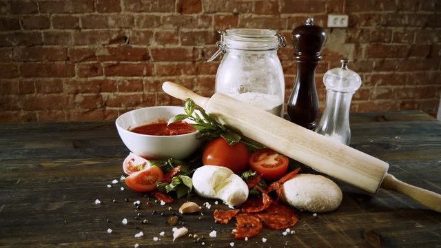 Close-up shot of ingredients for preparing a pizza on wooden table. 4K
