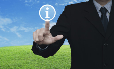 Businessman pressing information sign icon over green grass field with blue sky, Contact us concept