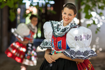 Keeping tradition alive: young woman in a richly decorated ceremonial folk dress/regional costume (Kyjov folk costume, Southern Moravia, Czech Republic) - obrazy, fototapety, plakaty