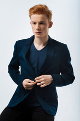 Thinking. Good-looking thoughtful red-haired young man wearing a black jacket and buttoning it up...